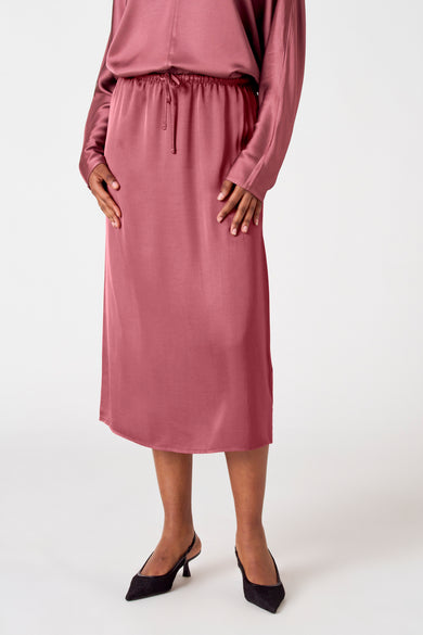 Robe rose d'Astrid Black Label, avec une ceinture élastique et des talons assortis.