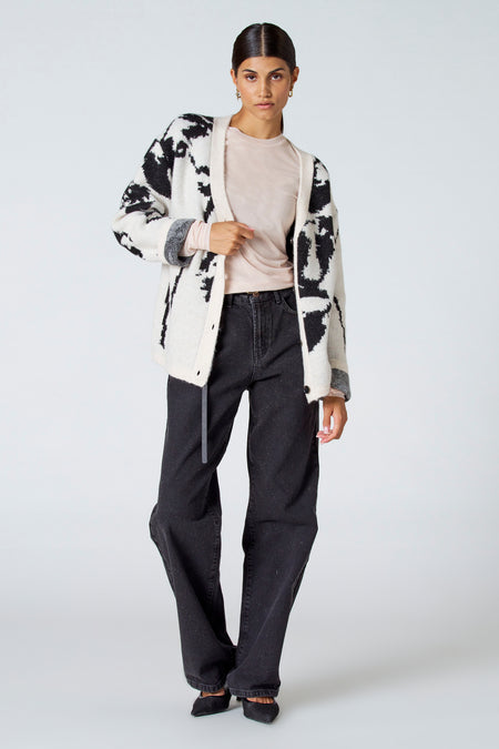 Ecru gilet van Astrid Black Label, met een opvallend zwart patroon, gedragen over een roze shirt en donkere jeans.
