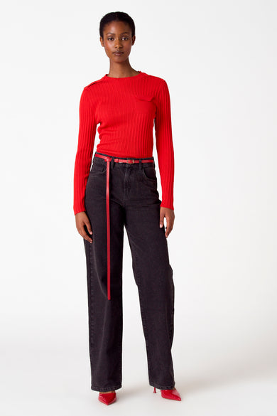 T-shirt rouge avec col rond d'Astrid Black Label, porté avec un jean noir et une ceinture rouge et des chaussures rouges.