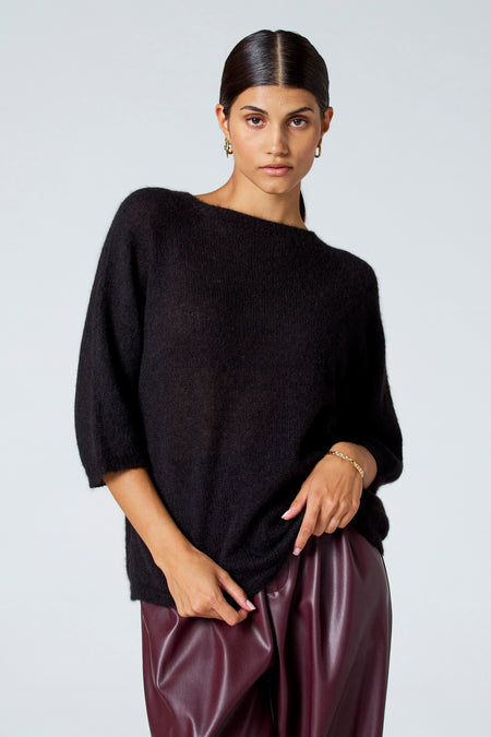 Zwarte trui met ronde hals van Astrid Black Label, met losse pasvorm en driekwart mouwen, gedragen met leren broek.
