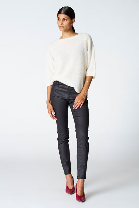 T-shirt écru avec col rond d'Astrid Black Label, porté avec un pantalon noir brillant et des baskets roses.