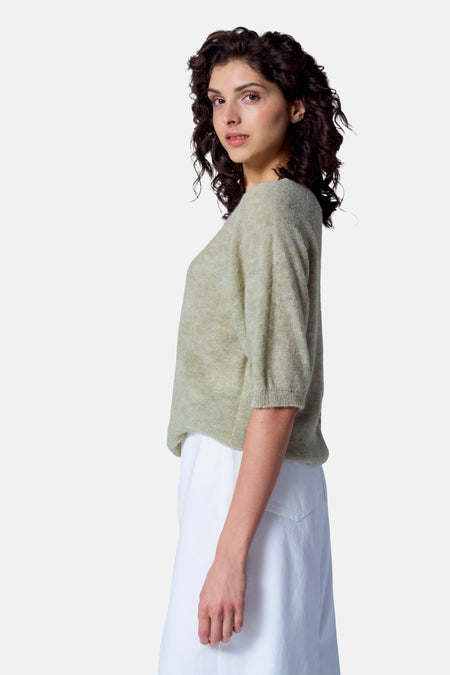 T-shirt vert avec col rond d'Astrid Black Label, à manches courtes et porté avec une jupe blanche.