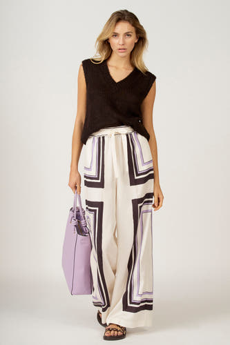 T-shirt marron d'Astrid Black Label, porté avec un pantalon à motif et une poche violette.