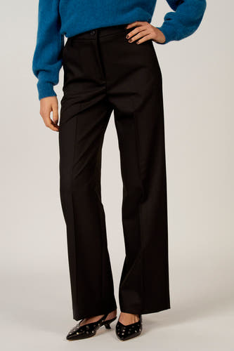 Zwarte broek van Astrid Black Label, gecombineerd met een blauwe trui en zwarte, spitse slingbacks met studs.
