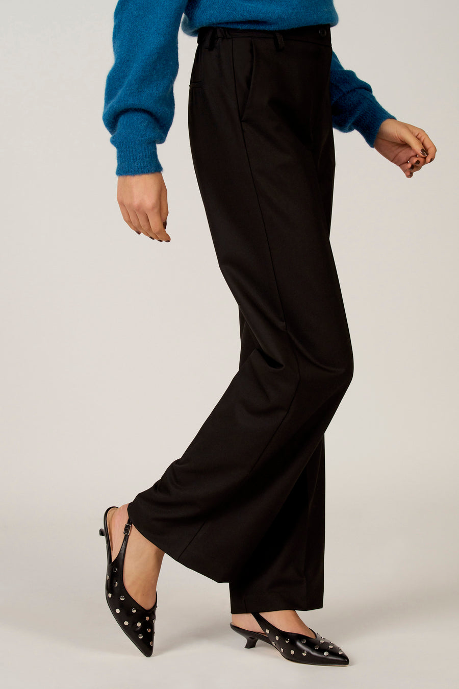 Zwarte broek van Astrid Black Label, met steekzakken en een rechte pijp, gedragen met zwarte, puntige muiltjes met studs.
