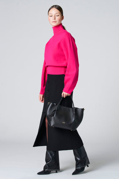 Blouse rose à col montant d'Astrid Black Label, portée avec une jupe noire à boutons et des bottes noires.