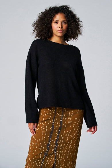 Pull noir avec col rond d'Astrid Black Label, associé à une jupe marron à imprimé dealmatien.