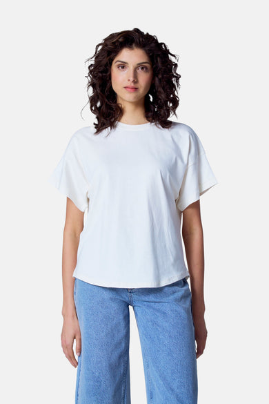 T-shirt écru à manches courtes d'Astrid Black Label, vu de derrière, associé à un pantalon bleu.