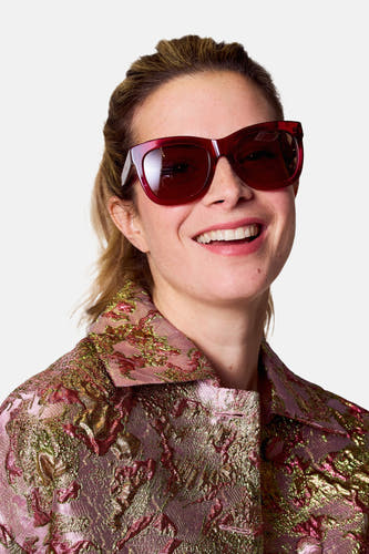 Lunettes de soleil roses d'Astrid Black Label, avec des verres marrons et un cadre anguleux.