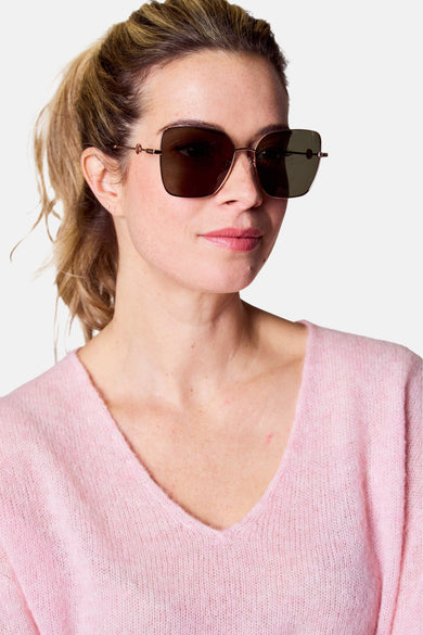 Roze zonnebril van Astrid Black Label, met een metalen montuur en gedempte glazen, gedragen met een roze trui.
