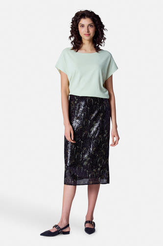 Zwarte rok van Astrid Black Label, met paillettenpatroon, gecombineerd met een lichtgroene top en zwarte schoenen.
