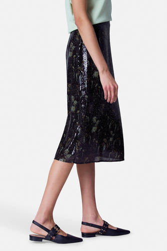 Zwarte rok van Astrid Black Label, met pailletten en een midi-lengte, gedragen met een lichtgroene top en zwarte slingback schoenen.