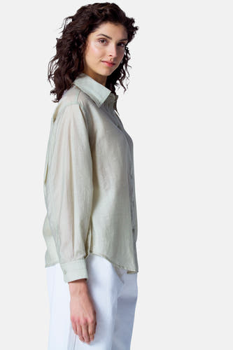 Blouse verte avec manches longues d'Astrid Black Label, dotée d'une légère texture et portée avec un pantalon blanc.