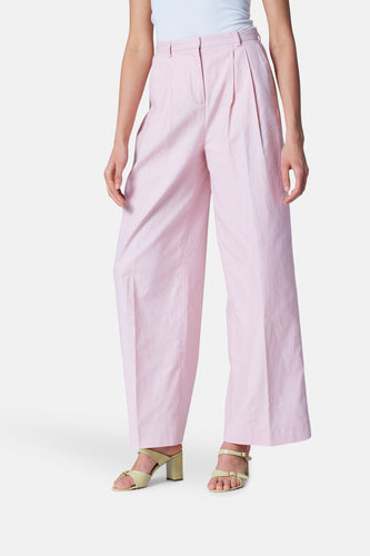 Roze, wijde pantalon met beige sandalen.
