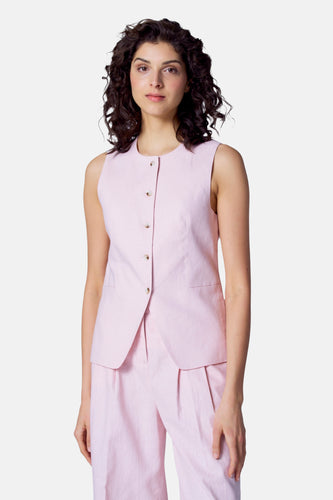 Vrouw in roze linnen pak, vest en pantalon, staand.