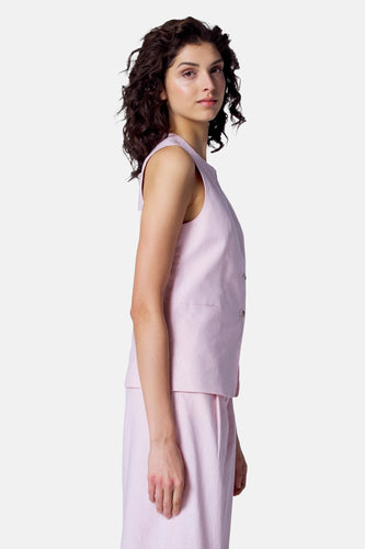 Vrouw in roze linnen vest en rok, zijwaarts kijkend.
