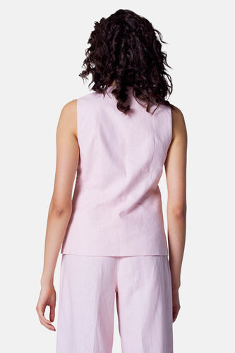 Achterkant van een vrouw in een roze mouwloze top en broek.