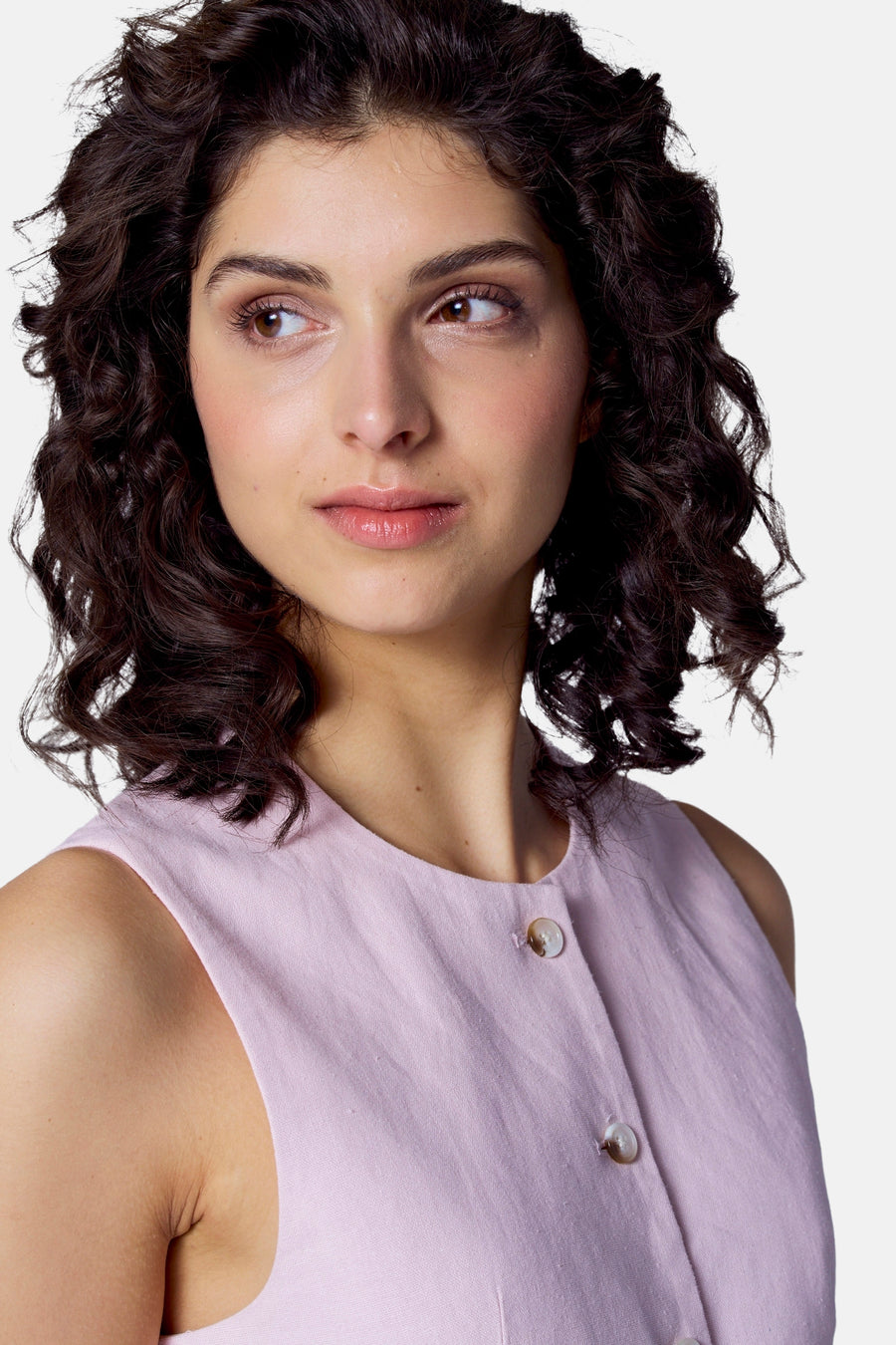 Vrouw met donker krullend haar, roze linnen jurk.