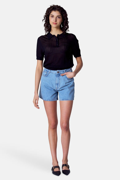 Polo noir à manches courtes d'Astrid Black Label, avec une subtile texture rayée verticale et porté avec des shorts en jeans.