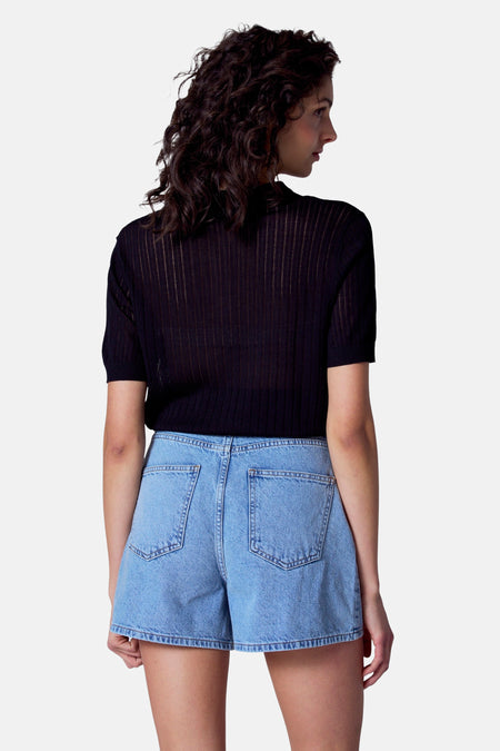 Polo noir à manches courtes d'Astrid Black Label, avec des rayures verticales sur le dos, associé à des shorts en denim bleu.