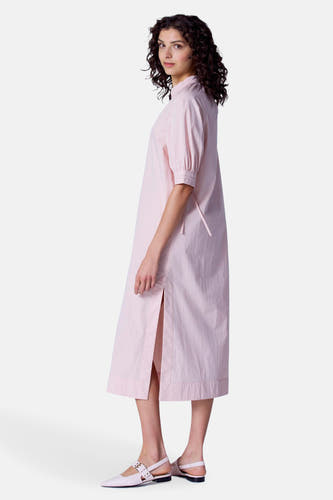 Robe rose à manches courtes d'Astrid Black Label, avec une fente latérale et des chaussures coordonnées.
