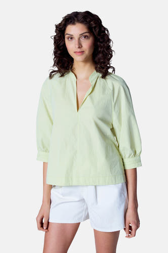 Blouse verte avec manches trois-quarts d'Astrid Black Label, avec une encolure ouverte et des shortts blancs.