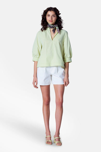 Groene blouse met driekwart mouwen van Astrid Black Label, met een halsdoek en witte shorts.
