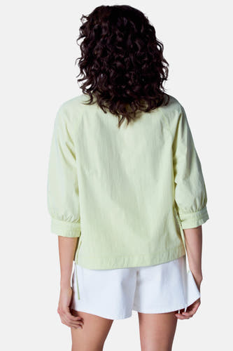 Blouse verte de Astrid Black Label Label man man man man man, v vueus ar ar ar une pantalon court blanc.