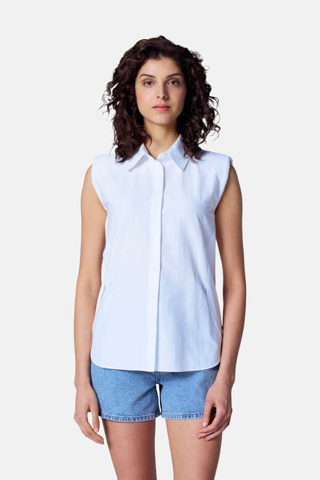 Blouse blanche à manches courtes d'Astrid Black Label, associée à des shorts en denim.
