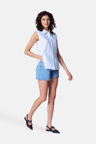 Witte blouse met korte mouwen van Astrid Black Label, gedragen met denim shorts en zwarte slingbacks met gespen.
