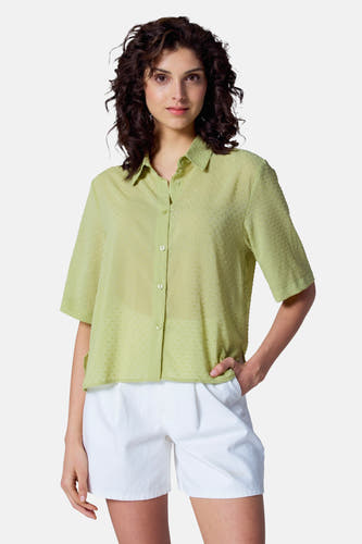 Groene blouse met korte mouwen van Astrid Black Label met een subtiel stippenpatroon, gecombineerd met witte shorts.
