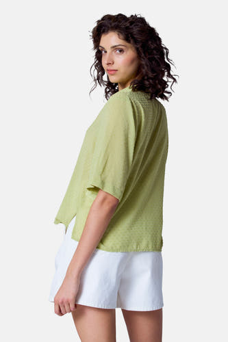 Groene blouse met korte mouwen van Astrid Black Label, met een subtiele stippen textuur, gedragen met witte shorts.
