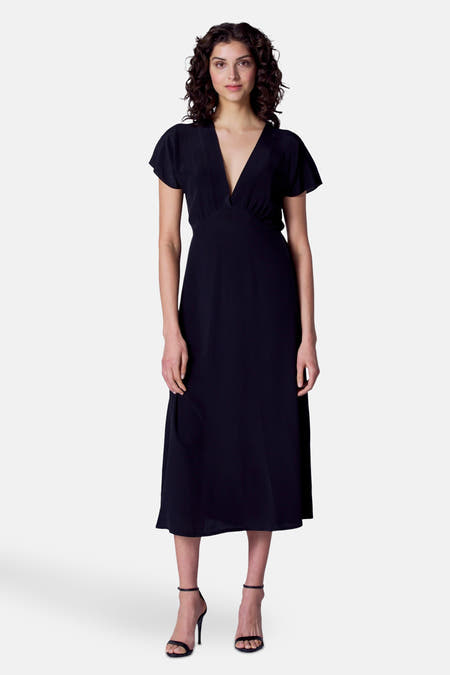 Robe noire à manches courtes d'Astrid Black Label, vue de derrière, avec une taille élastique et des talons noirs.