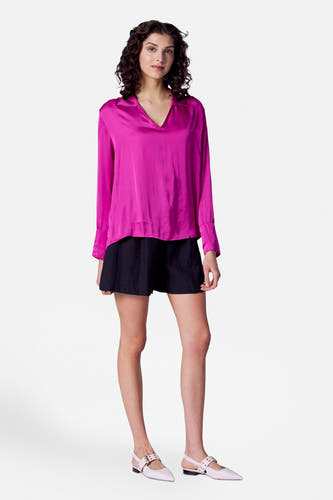 Zwarte short van Astrid Black Label, gedragen met een roze blouse met lange mouwen en lichte schoenen.