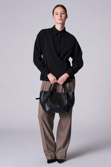 Blouse noire à manches longues d'Astrid Black Label, avec un détail de col et portée avec un pantalon kaki et des chaussures noires.
