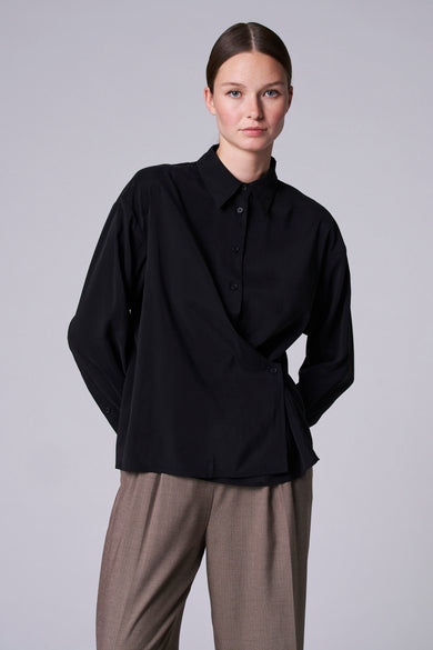 Blouse noire à manches longues d'Astrid Black Label, fermeture croisée et pantalon marron.