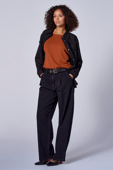 Zwarte jas in imitatieleer van Astrid Black Label, gedragen over een bruine top en een zwarte broek.