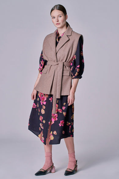 Taupe blazer van Astrid Black Label, gedragen over een bloemenjurk met roze sokken en zwarte schoenen.
