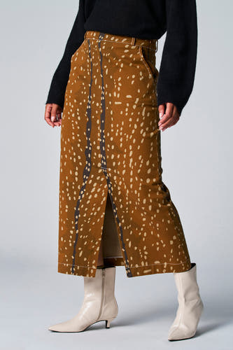 Bruine rok van Astrid Black Label met een gespikkelde print en een split, gecombineerd met een zwarte trui en crème laarzen.
