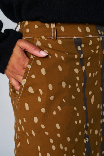 Bruine rok van Astrid Black Label met beige stippen en donkerblauwe strepen, met hand in de zak.
