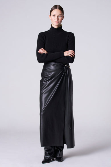 Zwarte rok van Astrid Black Label met drapering en gouden accenten, gecombineerd met zwarte coltrui en leren laarzen.
