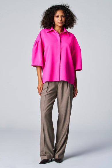 Blouse rose d'Astrid Black Label, à manches trois-quarts, portée avec un pantalon marron et des escarpins noirs.