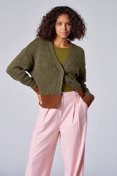 T-shirt vert avec col V d'Astrid Black Label, avec un bloc de couleur marron en bas et un pantalon rose.