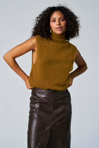 Groene debardeur van Astrid Black Label, gecombineerd met een bruine leren rok en gouden oorbellen.