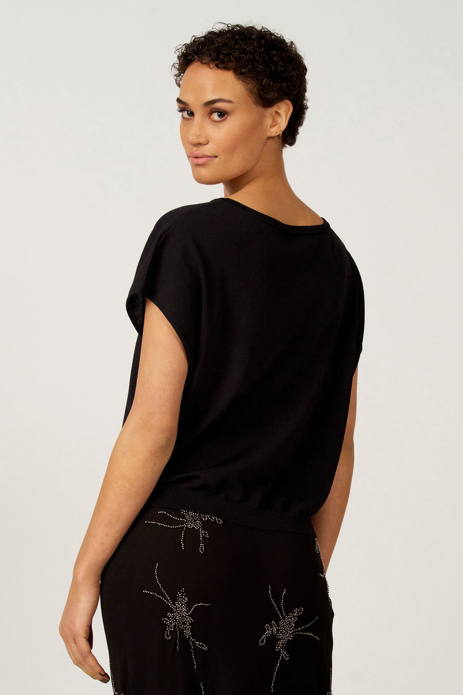 Zwarte trui met ronde hals van Astrid Black Label, met korte mouwen en decoratieve details op de bijpassende rok.
