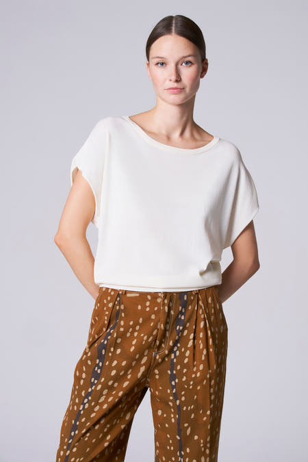 Ecru trui met ronde hals van Astrid Black Label, gedragen met bruine broek met stippenpatroon.
