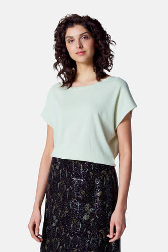 T-shirt vert avec col rond d'Astrid Black Label, associé à une jupe brillante avec paillettes.