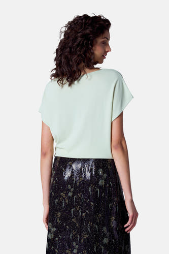 T-shirt vert avec col rond d'Astrid Black Label, associé à une jupe noire pailletée.