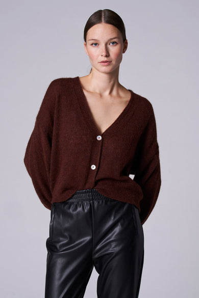 Bruin gilet van Astrid Black Label, met een V-hals en witte knopen, gecombineerd met een zwarte broek.

