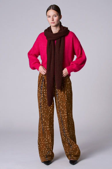 Roze gilet van Astrid Black Label, met een fuzzy textuur, gedragen over een bruine top en patroonbroek.